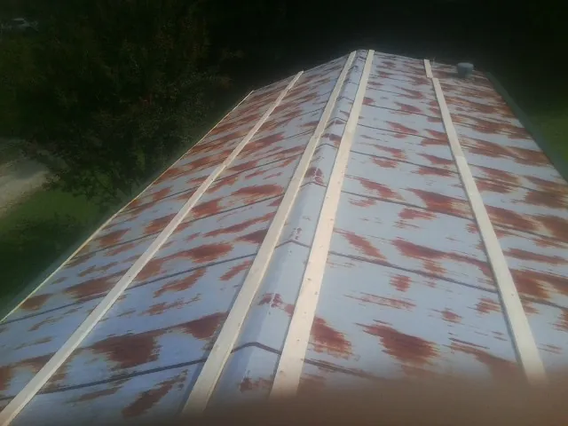 Rusted metal roof panels with new wood purlins before replacement — Storm Damage Roof Repair in South Lyon by Roofing Brothers