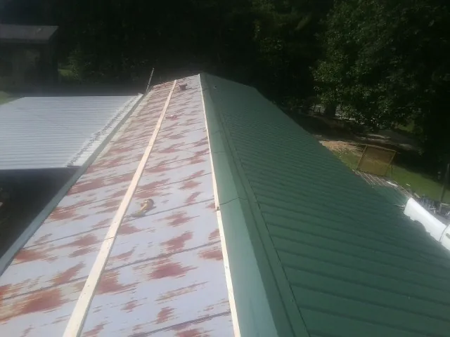 Old rusted panels beside newly installed green metal roofing — Wind Damage Roof Repair by Roofing Brothers in South Lyon