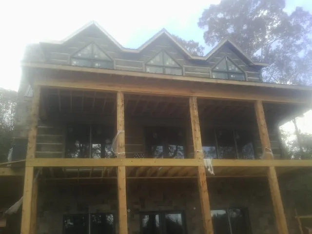 Dormers and porch framing on a large log home under construction — Roof Coating work by our crew in South Lyon