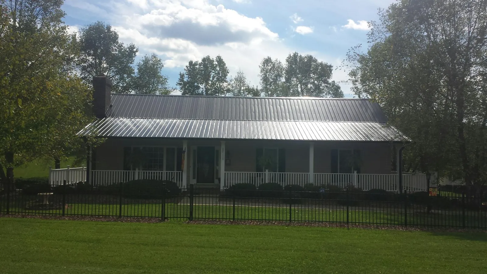 Gray metal roof on a brick ranch with a full width front porch — Gutter Guard Installation work by our crew in South Lyon