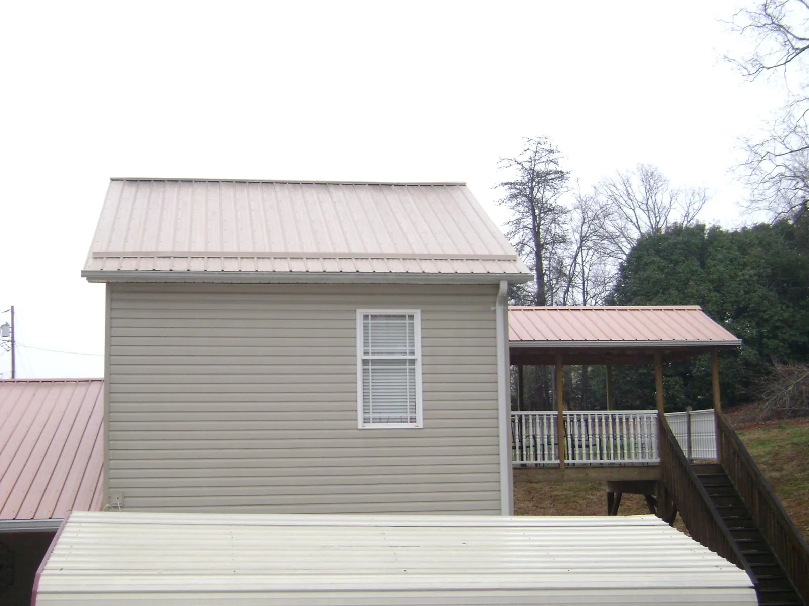 Tan metal roofs on a two story addition and attached porch, from a Roof Replacement job in South Lyon