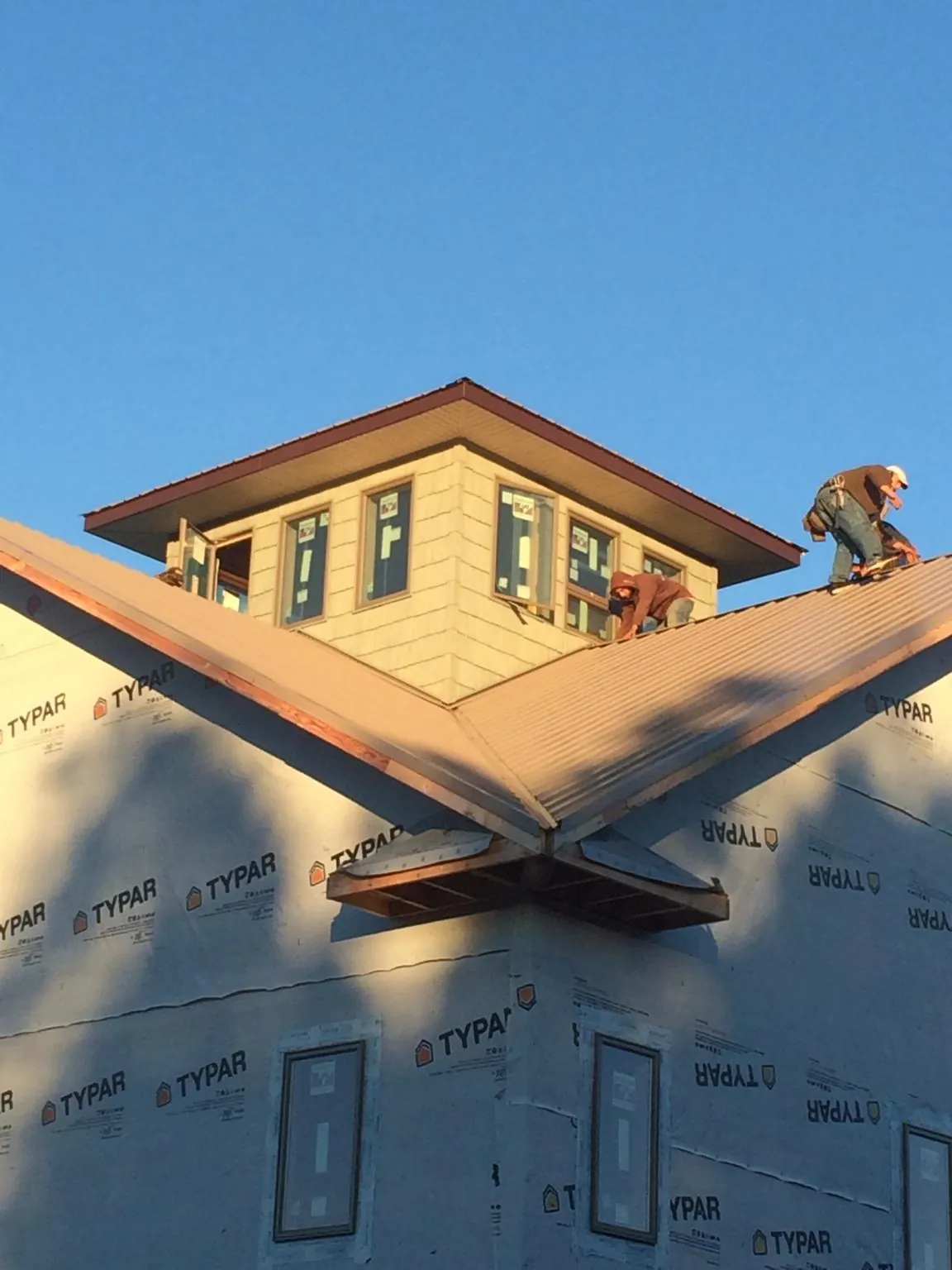 Roofers working around a rooftop cupola on a new metal roof at sunset — Roof Waterproofing in South Lyon by Roofing Brothers